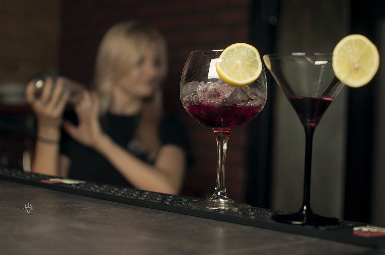 Kolorowe drinki na barze i praca zespołu w tle.