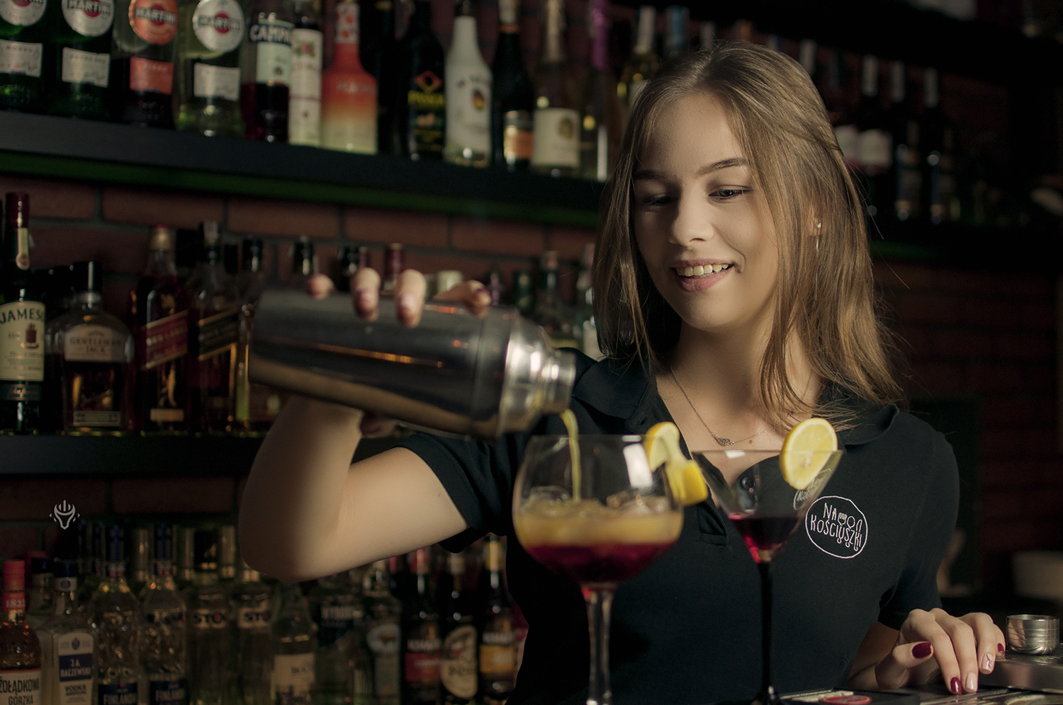 Barmanka nalewa napój podczas pracy.