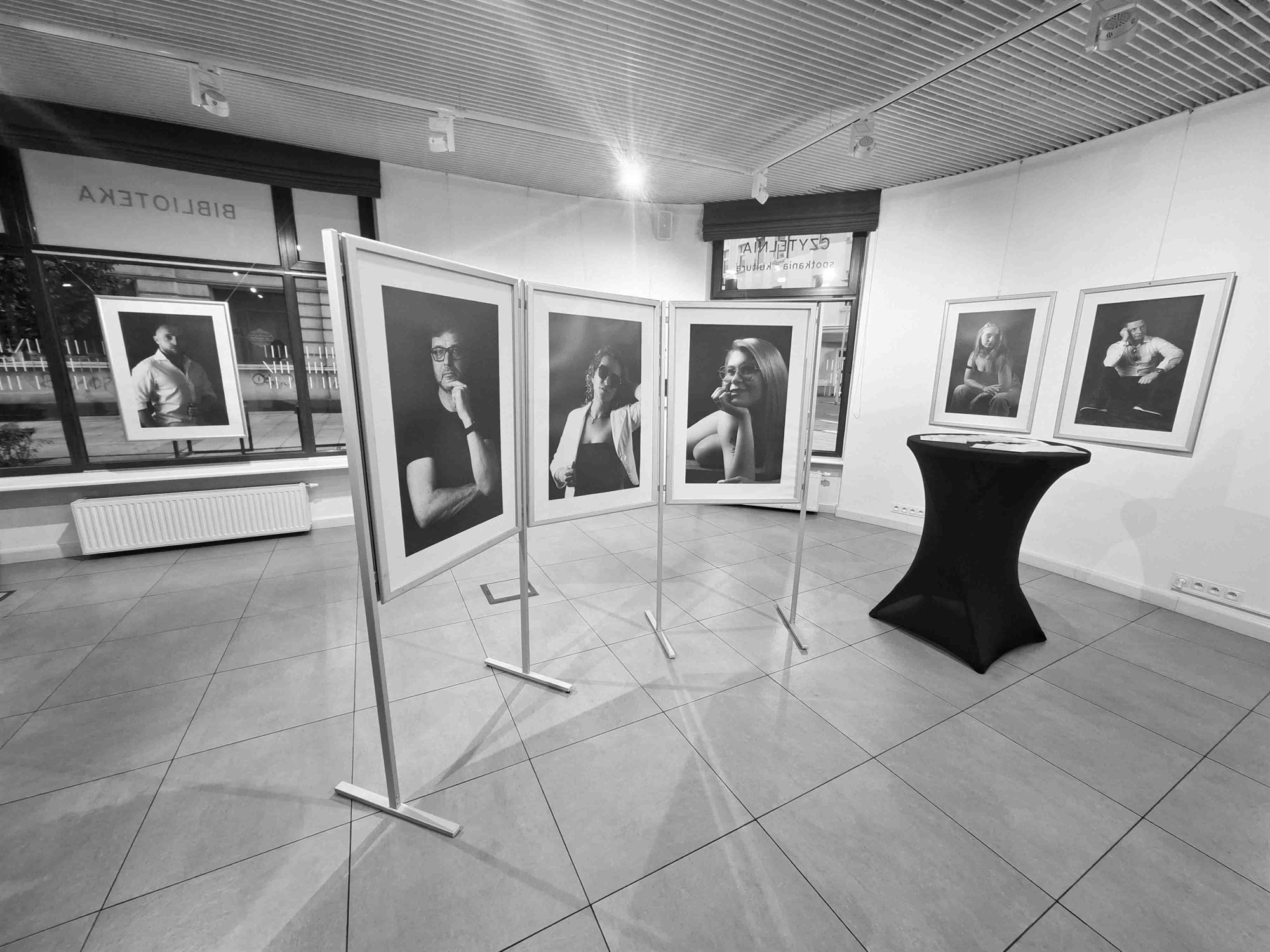 Fotografie w ramach ustawione na stojakach w galerii.