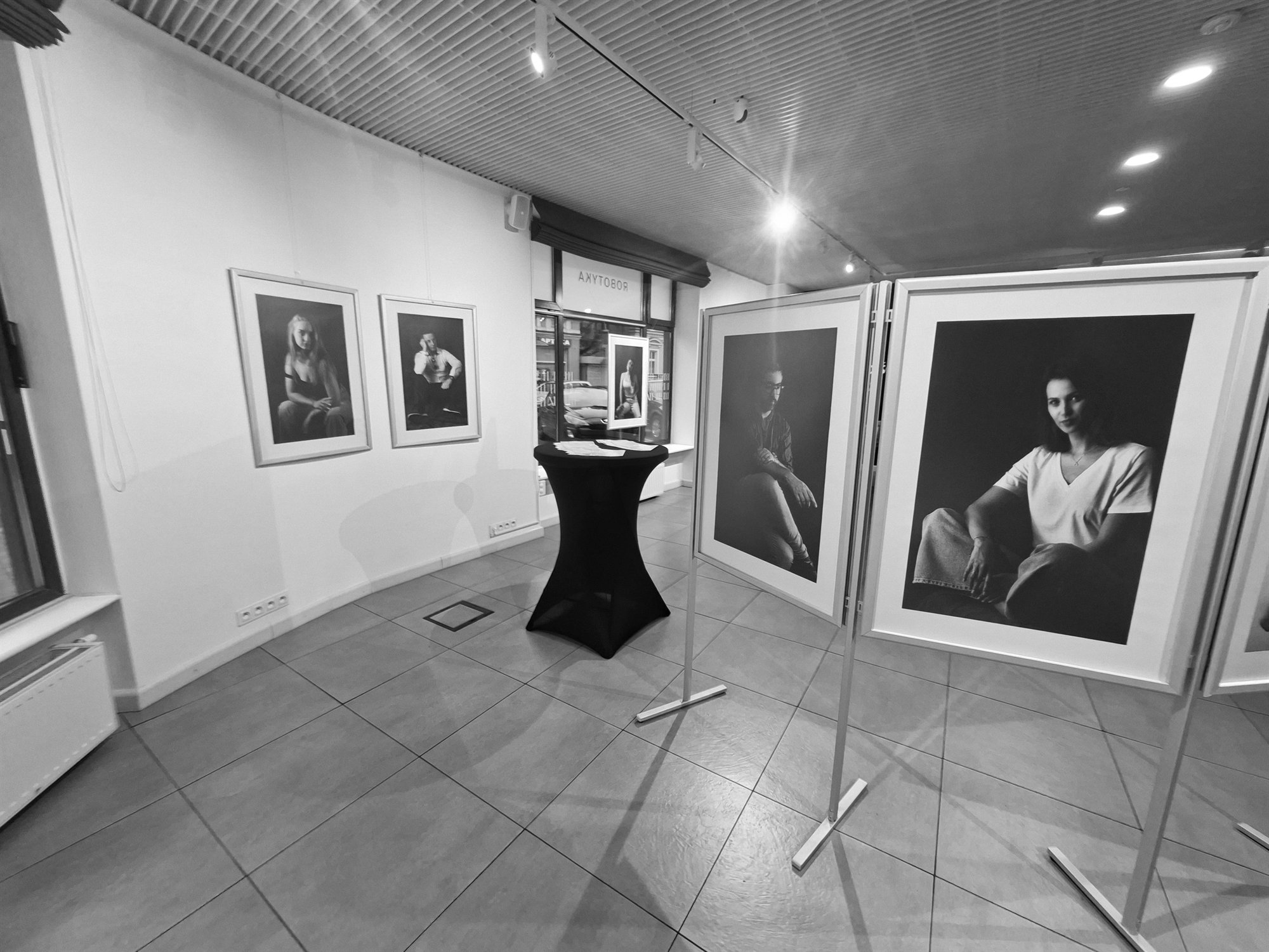 Sala galerii z ekspozycją portretów w ramach.